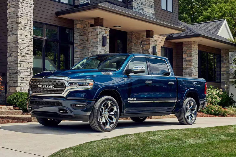 The 2023 Ram 1500 parked in the driveway of a large house.
